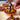 A hand decorates a tart in the Chocolate Tarts Masterclass with chocolate swirls, mousse, and yellow fruit on crisp pâte sablée. Other chocolate pastries appear in the background on a white surface.