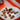 A white plate with Maison Marou’s Chocolate Workshop Masterclass pieces—stars, squares, and a rose—displayed on an orange surface. The plate features the Maison Marou logo.