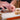 Close-up of hands assembling French macarons in the Macarons Masterclass, adding Marou chocolate filling on a white surface. Completed and unassembled macarons appear in the background.