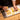 In the Pâte à Choux Masterclass, egg wash is brushed onto piped choux shapes—like cream puffs, eclairs, and swirls—set on a parchment-lined baking sheet.